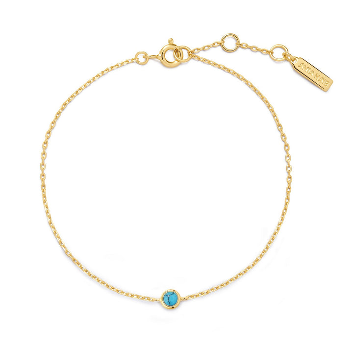 Gold bracelet with a turquoise stone on a white background