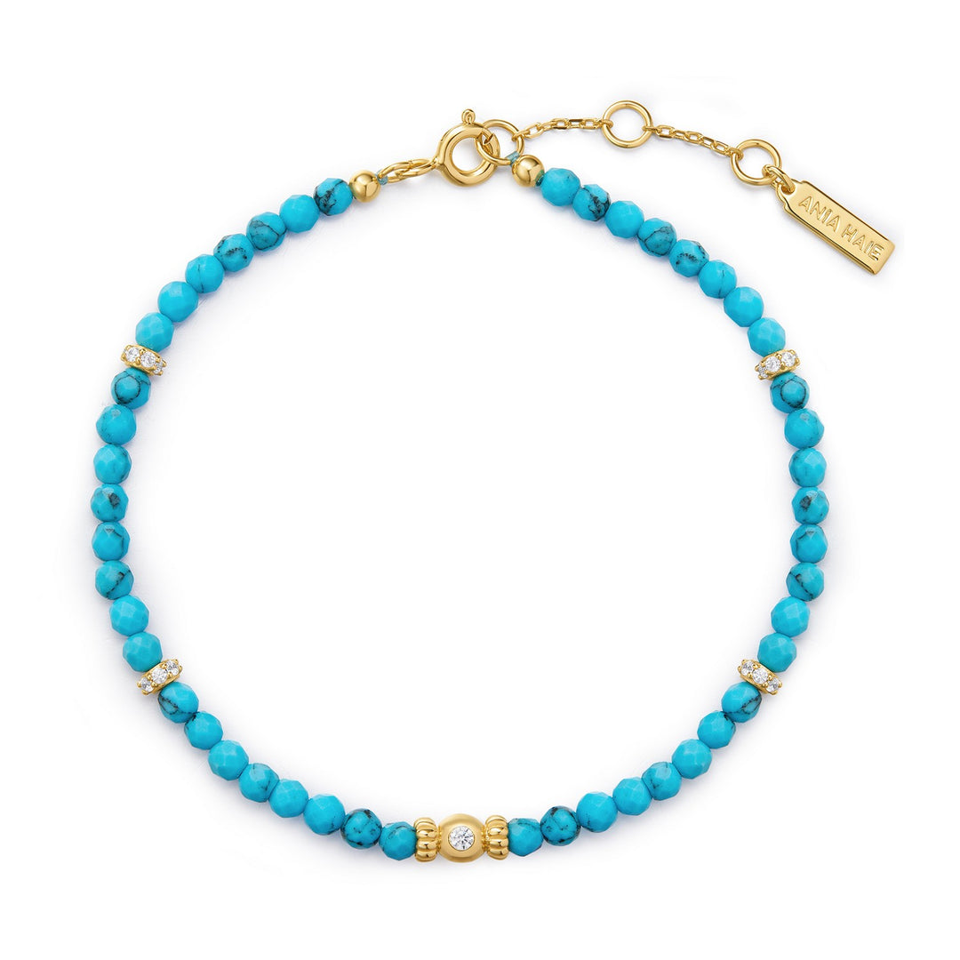 Turquoise beaded bracelet with gold accents on a white background
