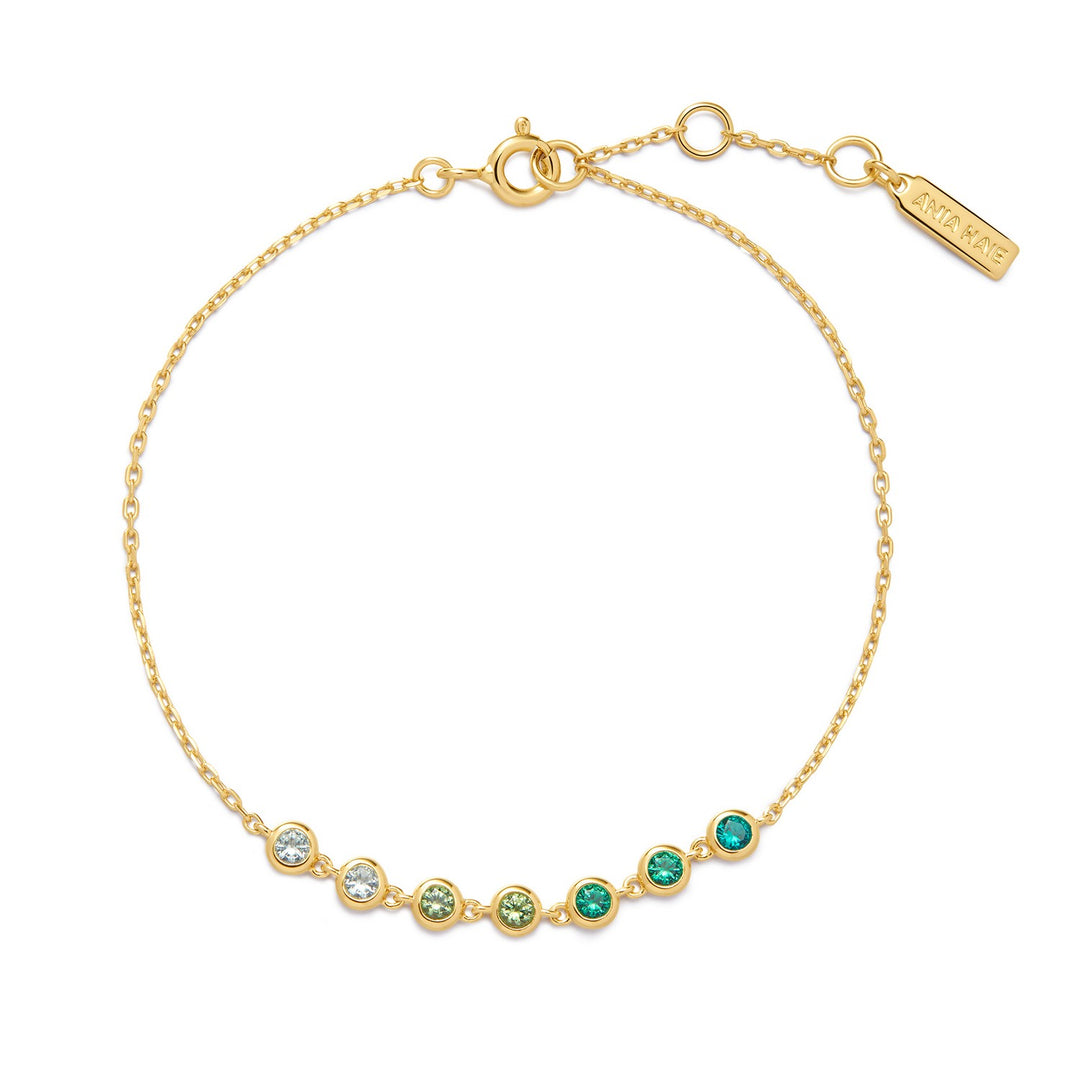 Gold bracelet with green and clear gemstones on a white background