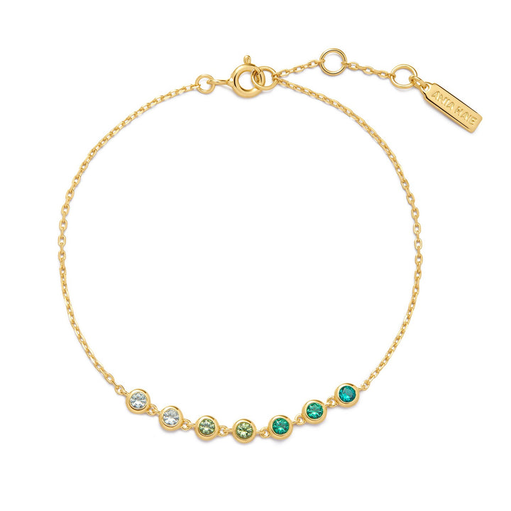 Gold bracelet with green and clear gemstones on a white background