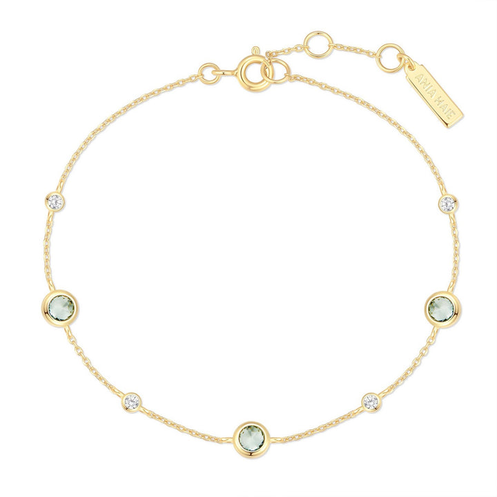 Gold bracelet with green gemstones on a white background