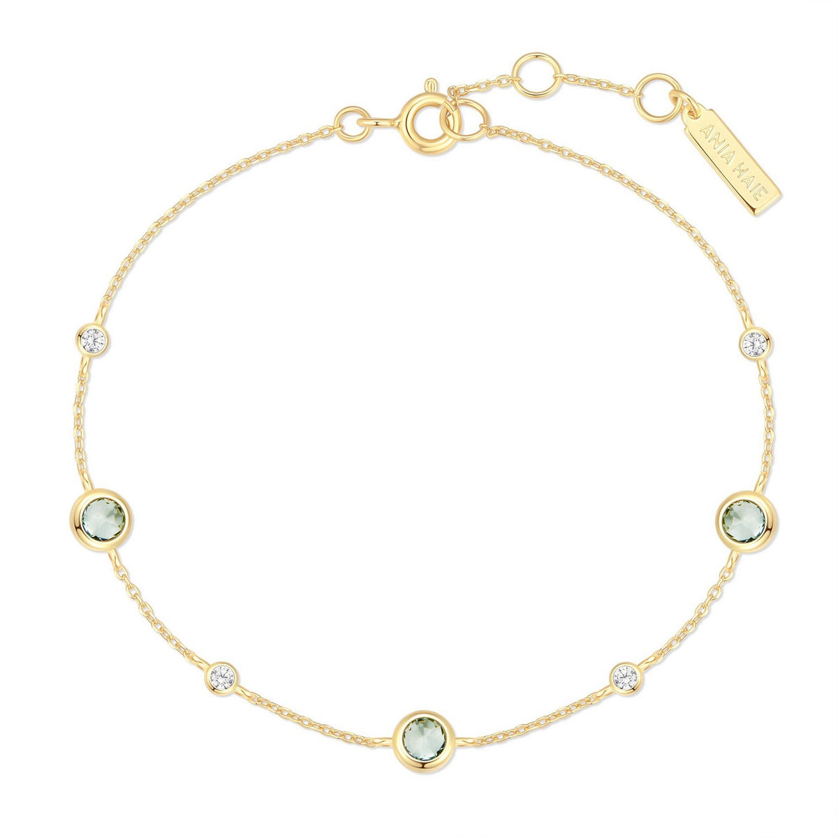 Gold bracelet with green gemstones on a white background
