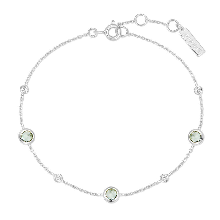 Silver bracelet with green gemstones on a white background