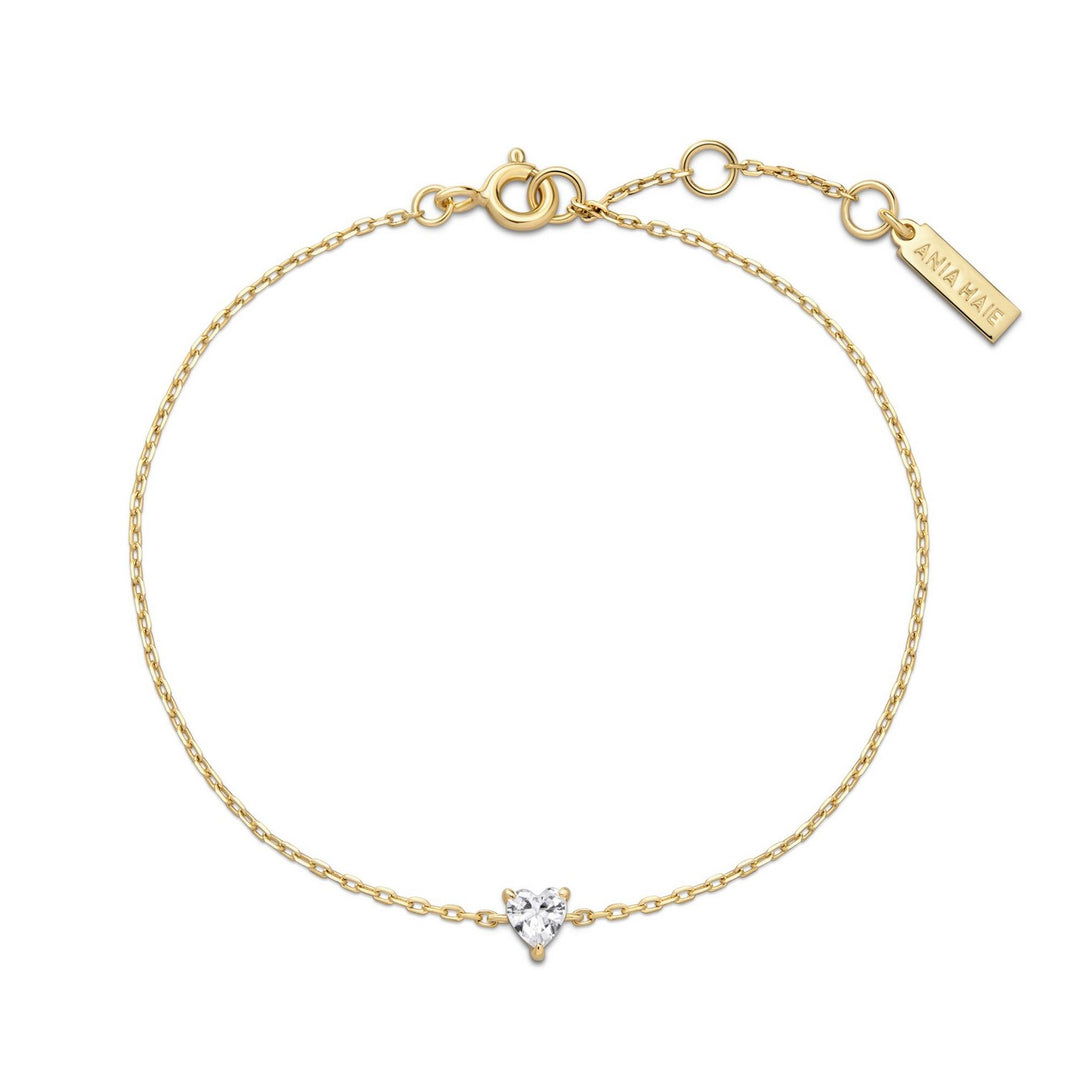 Gold bracelet with a heart-shaped diamond charm on a white background