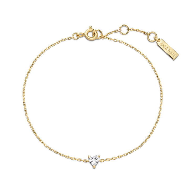 Gold bracelet with a heart-shaped diamond charm on a white background