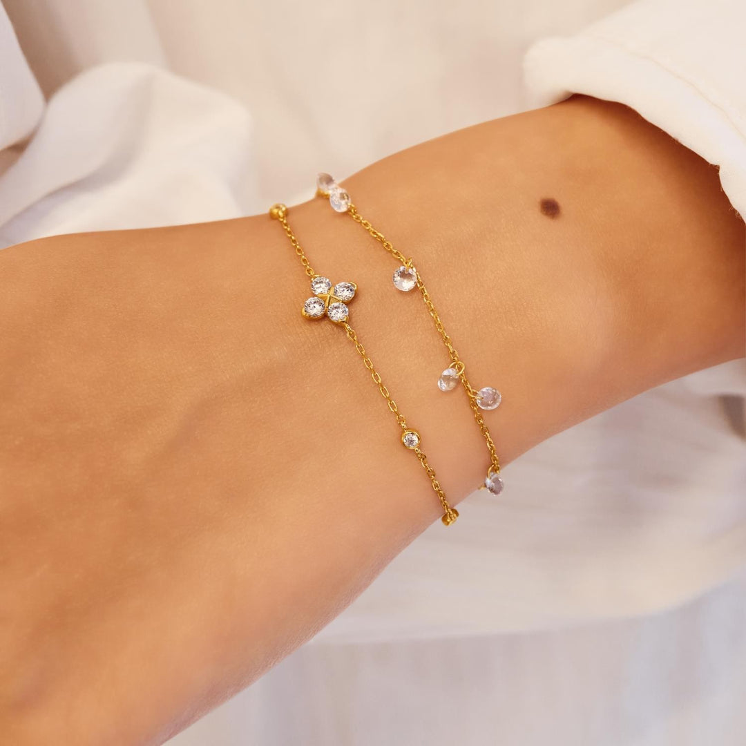 Gold bracelet with clear stones on a wrist against a white background