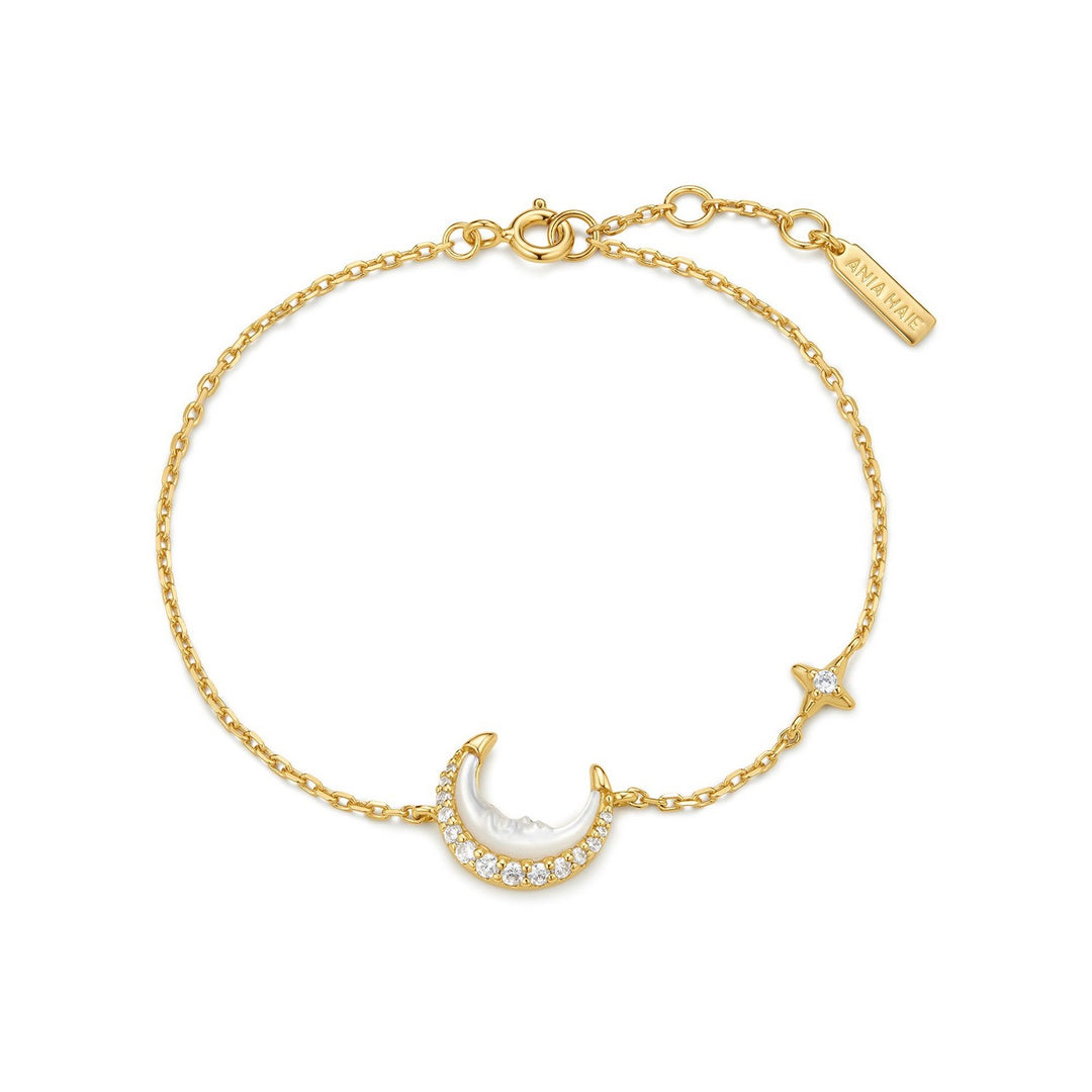 Gold bracelet with moon and star charms on a white background