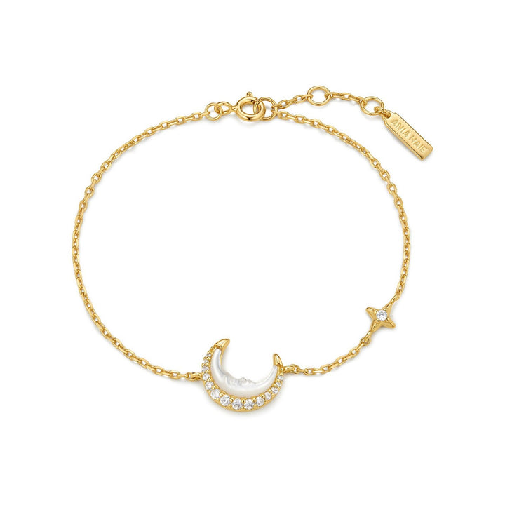 Gold bracelet with moon and star charms on a white background