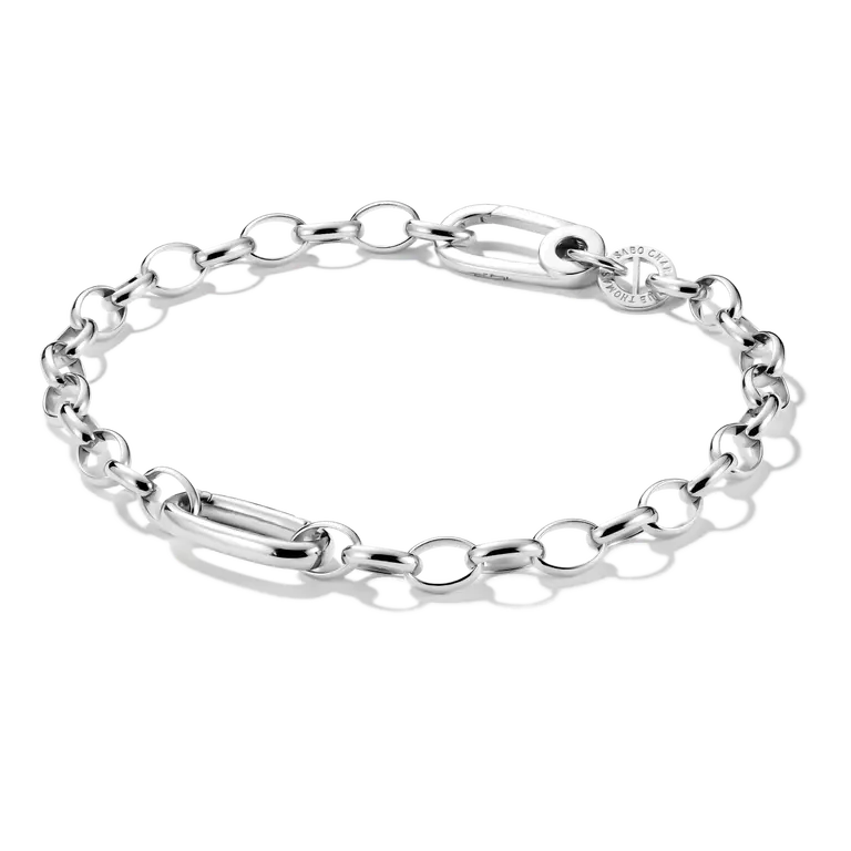 A silver chain link bracelet with a combination of oval links, a polished bar link, and a small round charm, displayed on a clean white background.