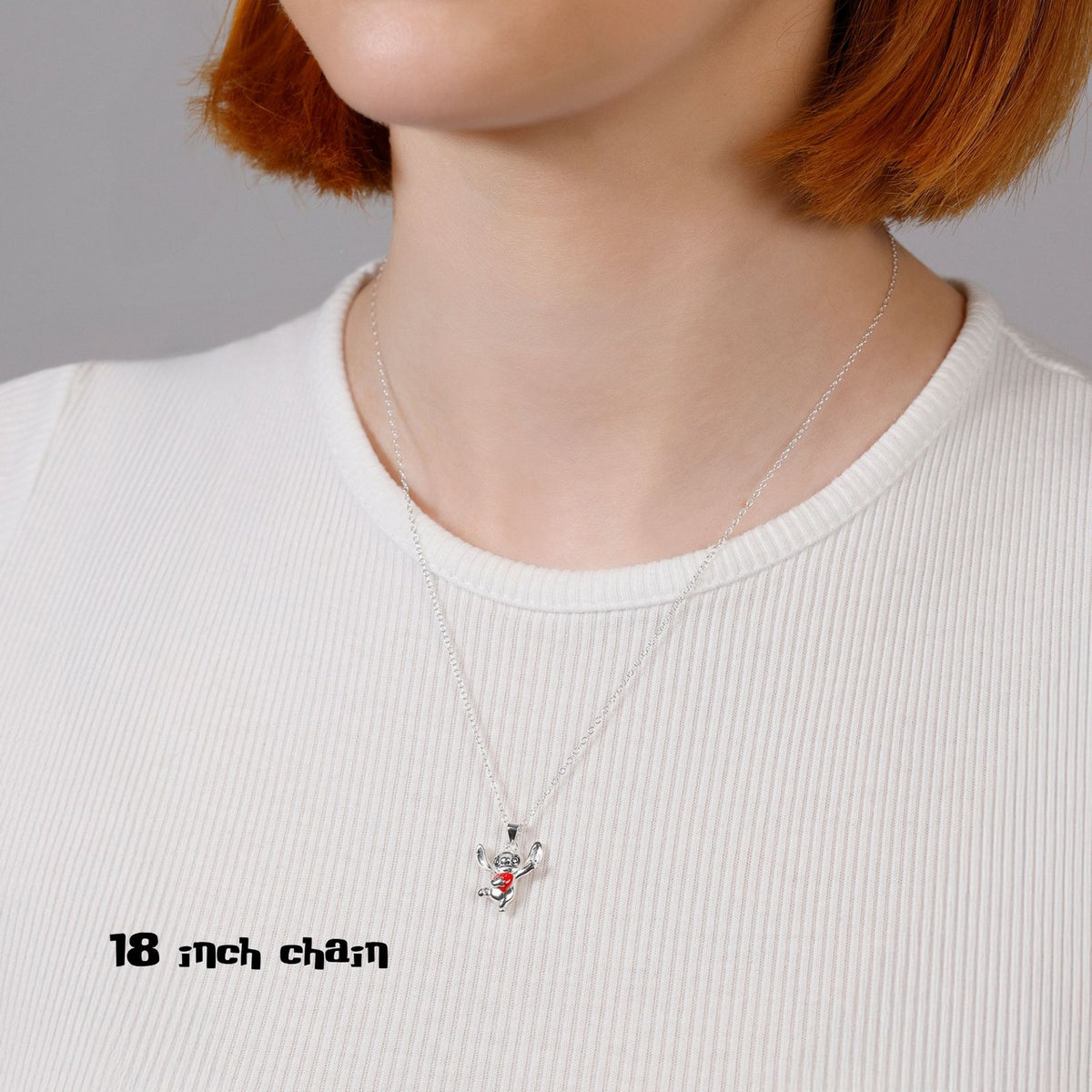 Person wearing a necklace with a small pendant on a plain background