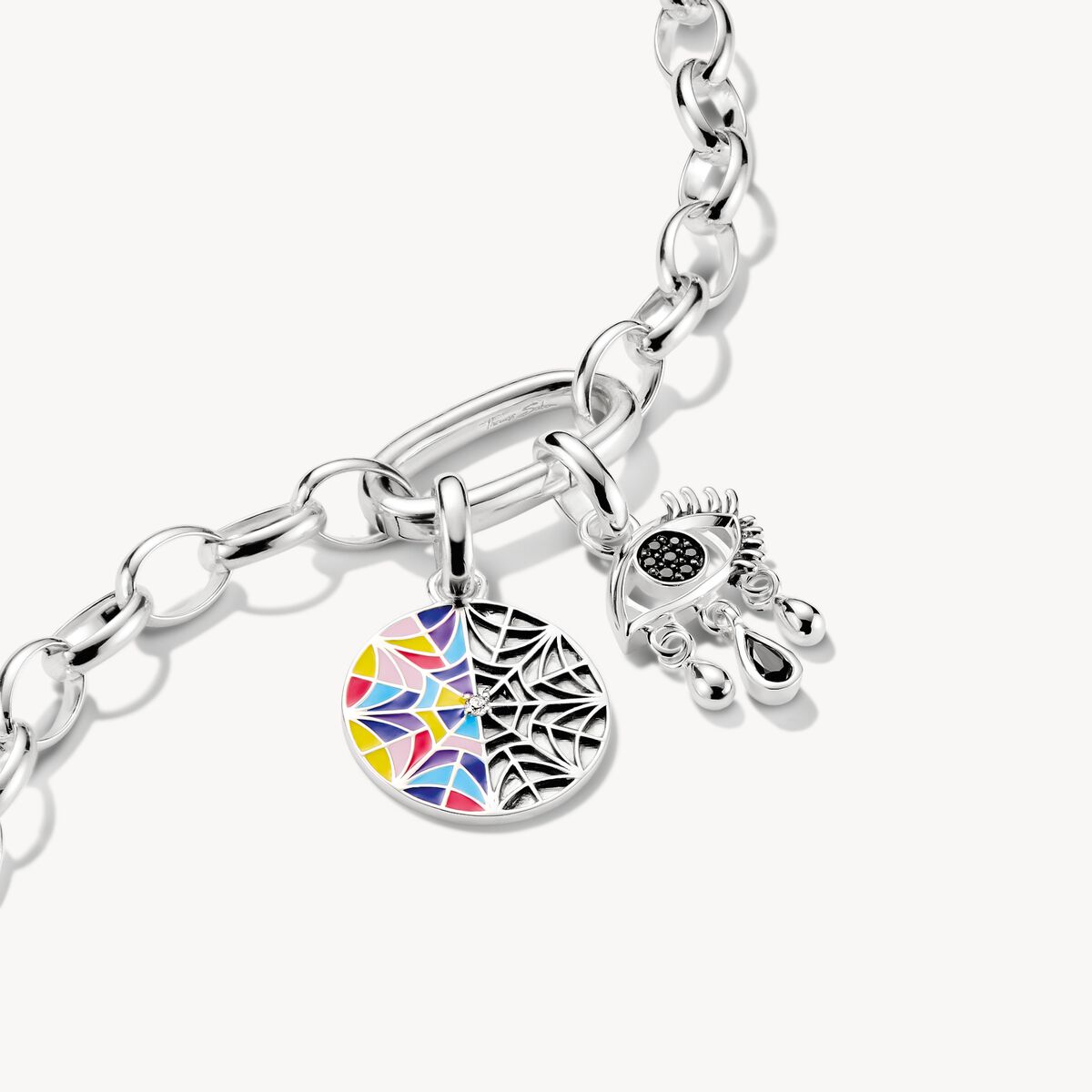 Silver eye-shaped pendant with a tear on a white background