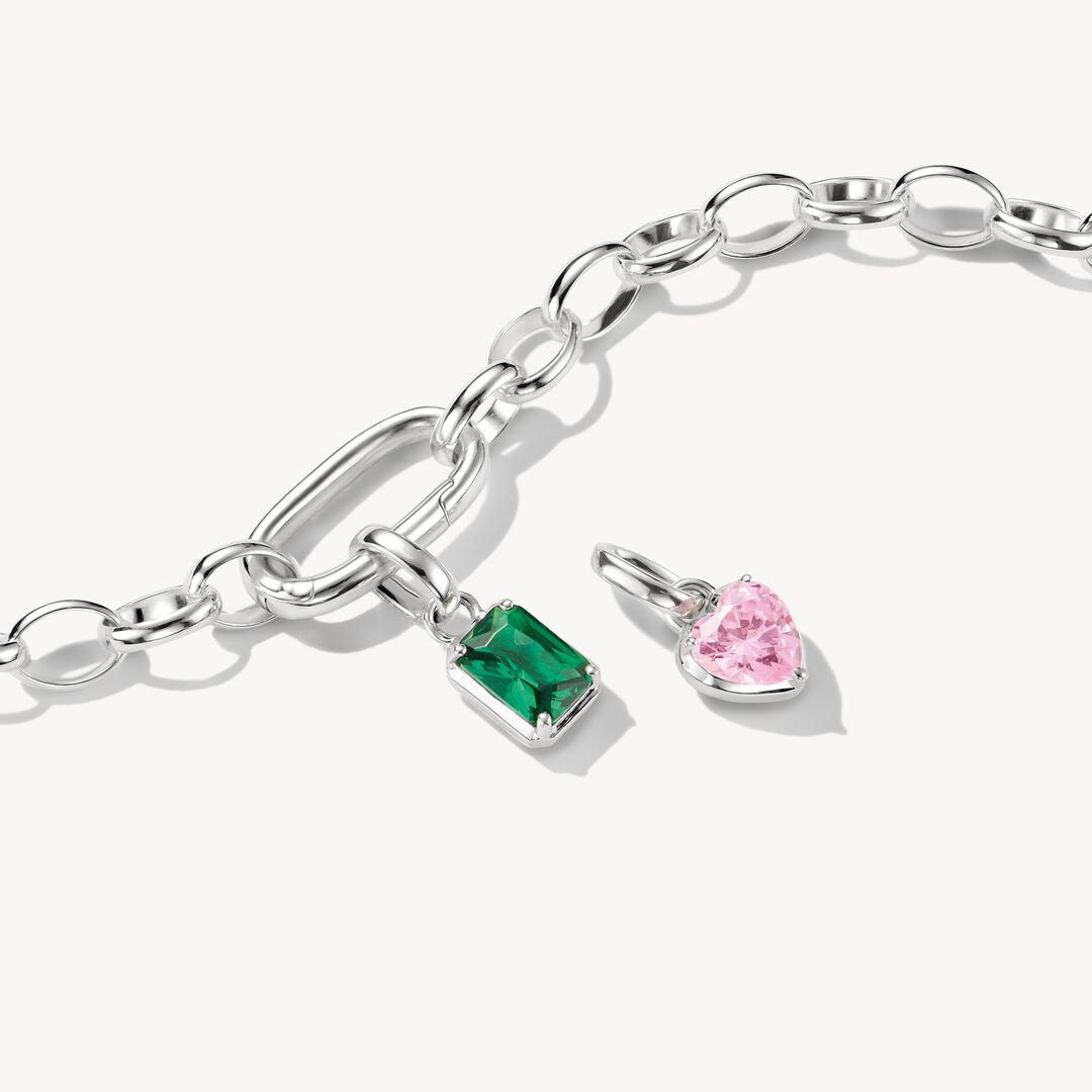 Silver bracelet with two charms, one green and one pink, on a white background