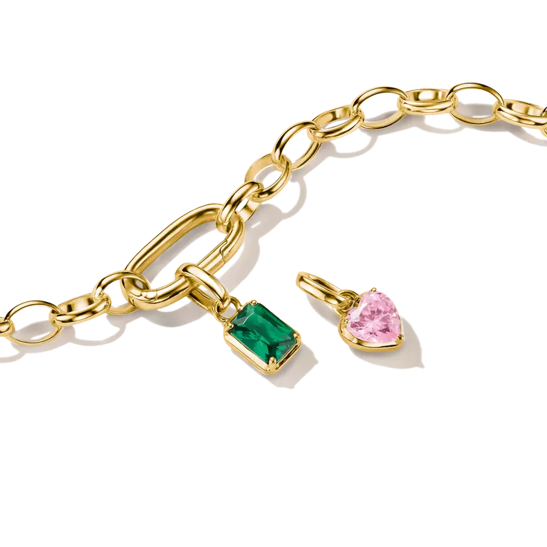 Gold chain bracelet with a rectangular green gemstone pendant and a heart-shaped pink gemstone pendant, shown on a clean white background.