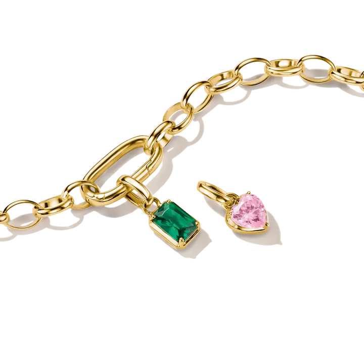 Gold chain bracelet with a rectangular green gemstone pendant and a heart-shaped pink gemstone pendant, shown on a clean white background.