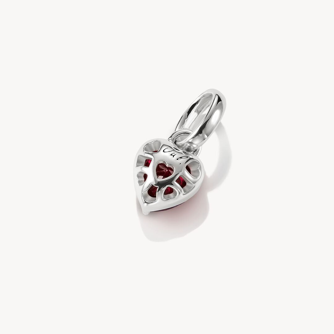 Silver heart-shaped pendant with red stones on a white background