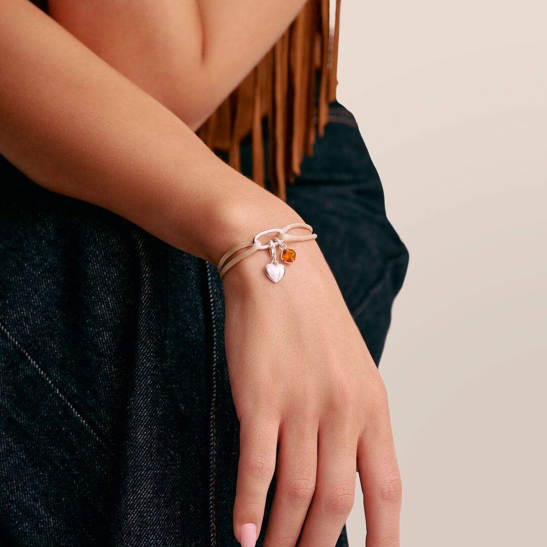 Close-up of a person's wrist wearing a bracelet with heart-shaped charms.
