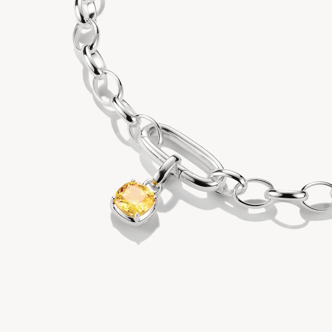 Silver bracelet with a yellow gemstone charm on a white background