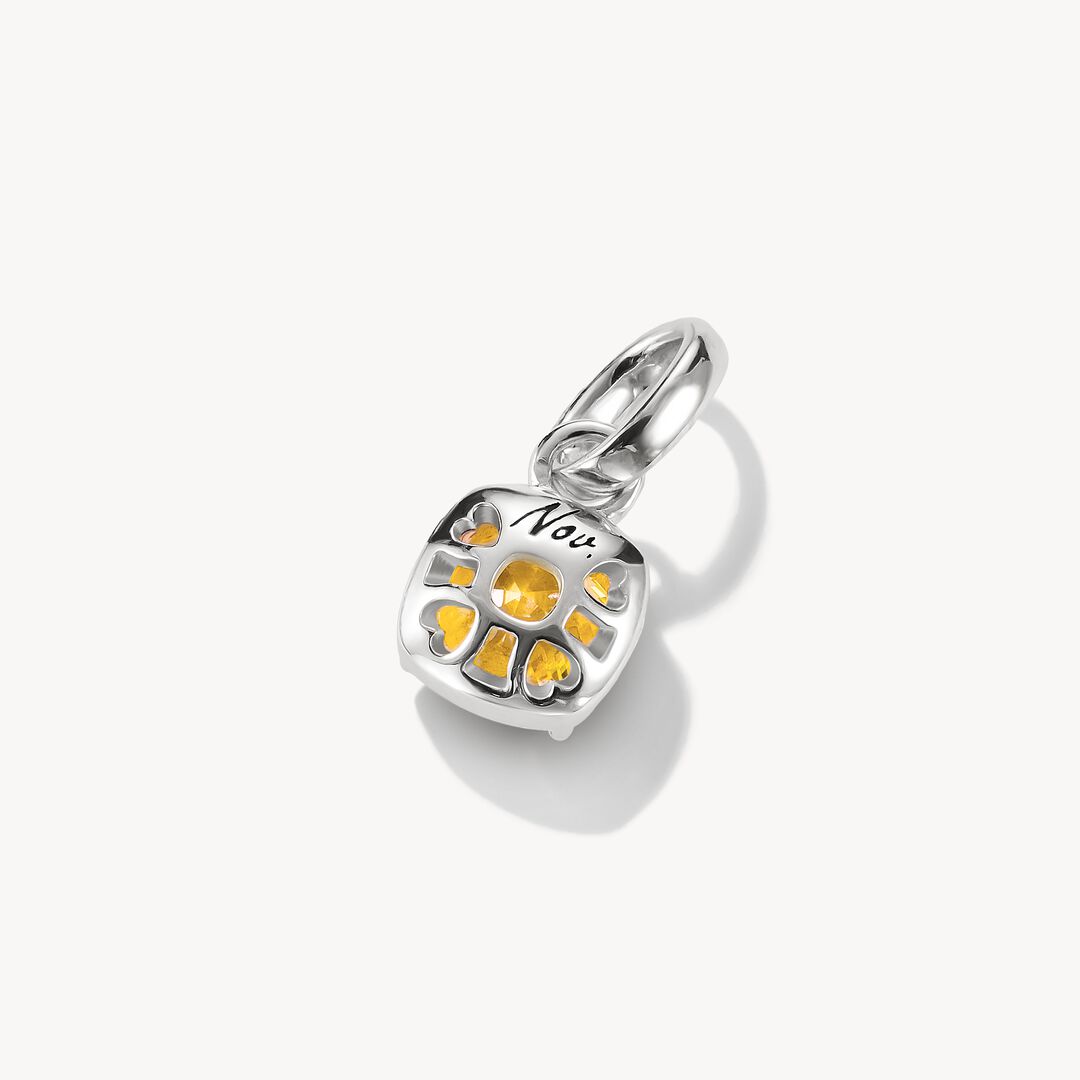 Silver pendant with a yellow gemstone on a white background