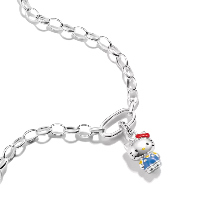 A silver link chain bracelet featuring a small Hello Kitty charm with white enamel, a red bow, and blue clothing, shown on a clean white background.
