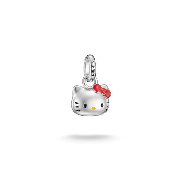 A silver Hello Kitty charm pendant with a red bow and small yellow nose, shown on a clean white background with a soft shadow below.