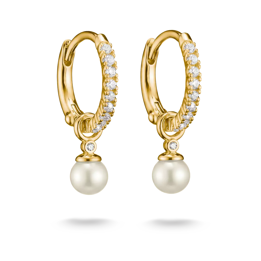 A pair of gold huggie hoop earrings with pavé-set clear stones and a dangling white pearl, shown on a clean white background.