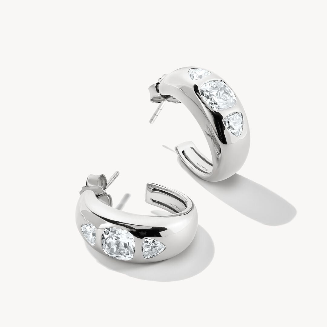 Silver hoop earrings with clear gemstones on a white background