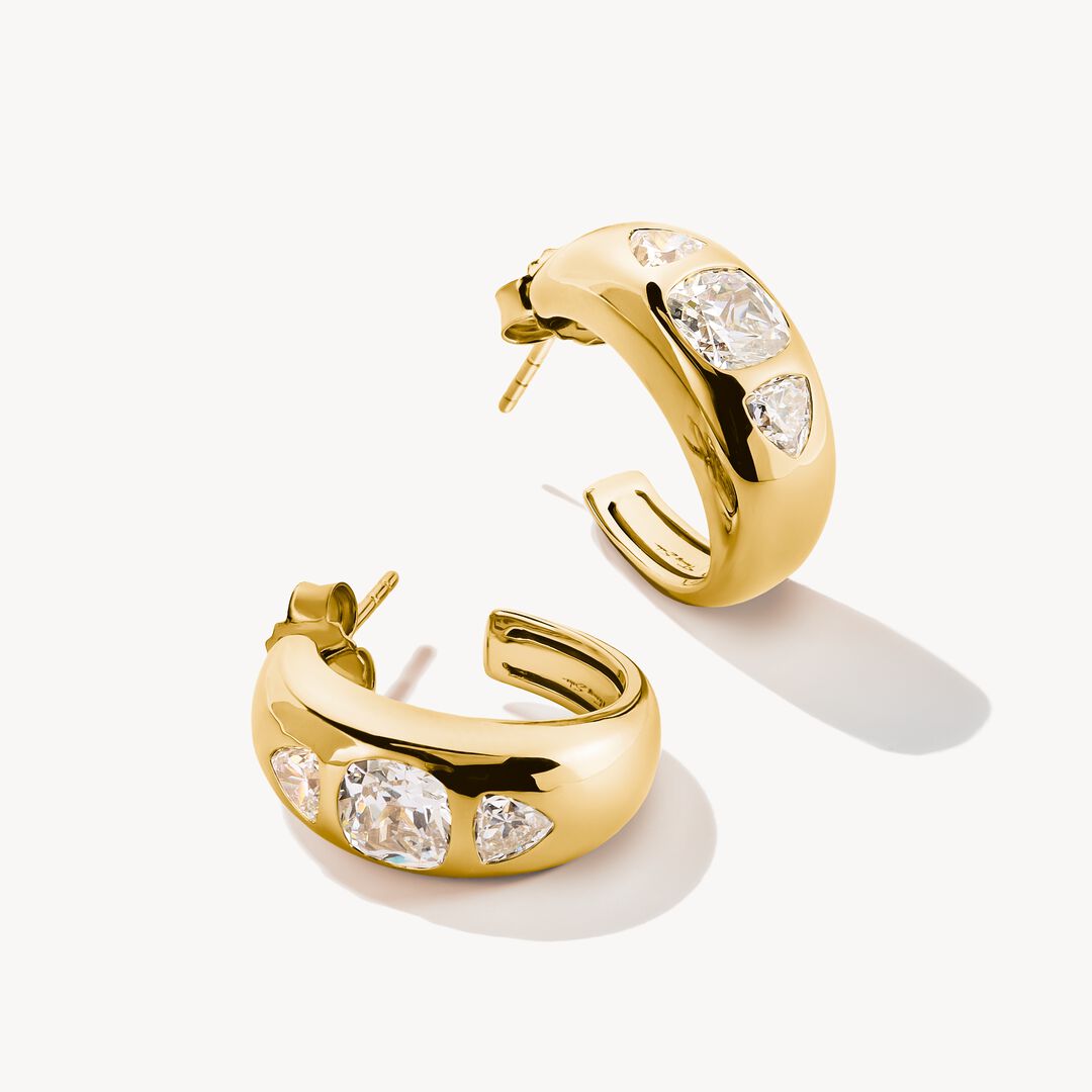 Gold hoop earrings with clear gemstones on a white background
