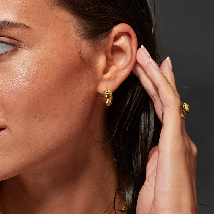 Close-up of a woman wearing gold earrings and a ring