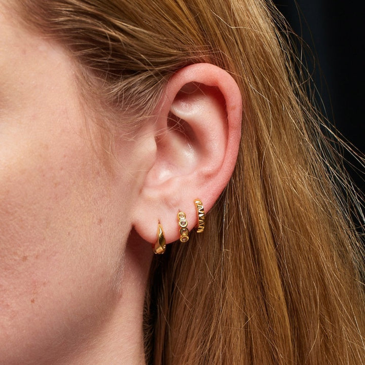 Close-up of an ear wearing gold hoop earrings 
