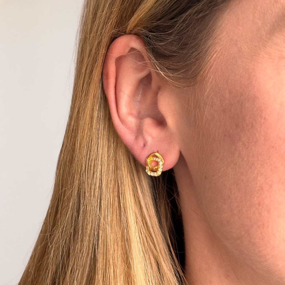 Close-up of a person wearing a gold earring with a yellow gemstone 