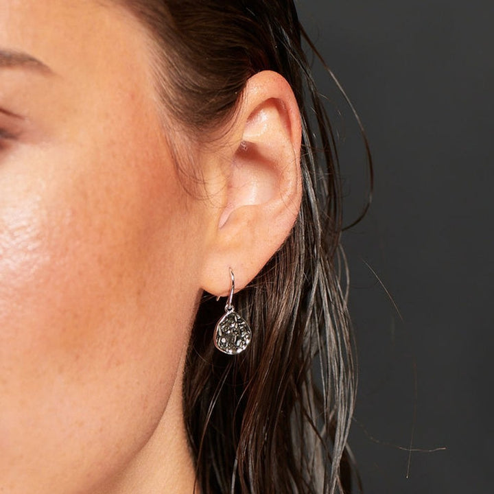 Close-up of an ear wearing a silver earring 