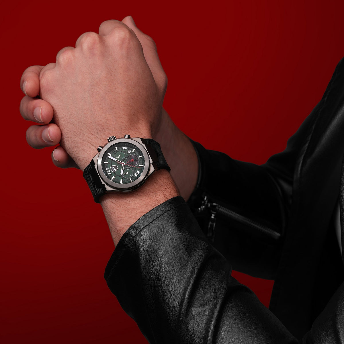 Hand wearing a black wristwatch with a red background