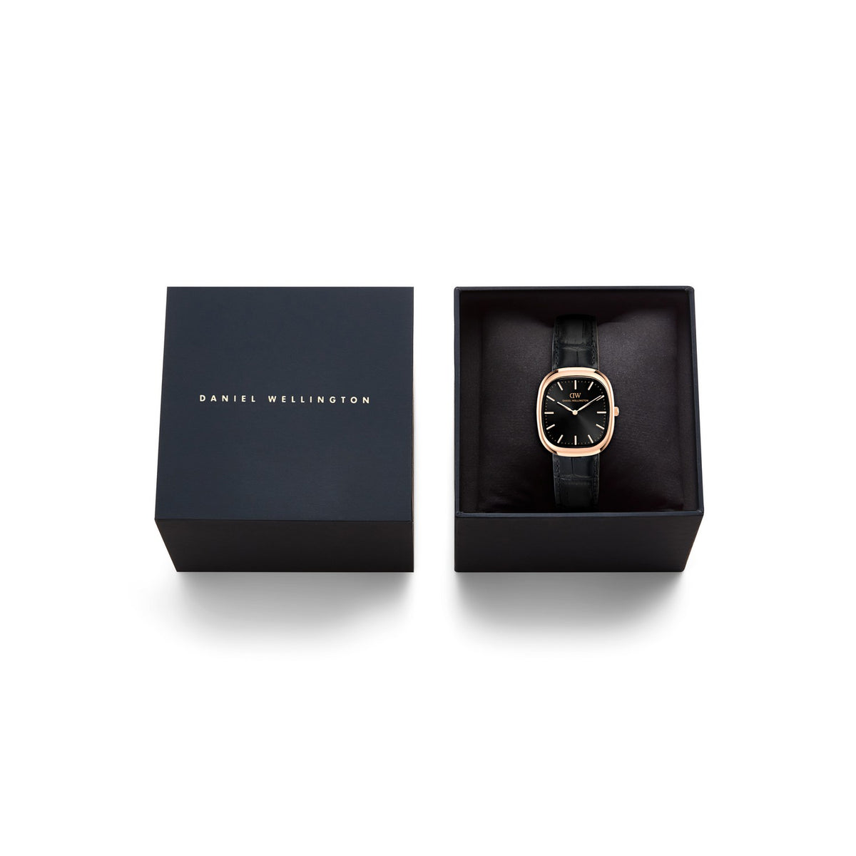 Daniel Wellington watch with a black leather strap and gold-toned case, displayed inside an open black presentation box next to its closed lid on a white background.
