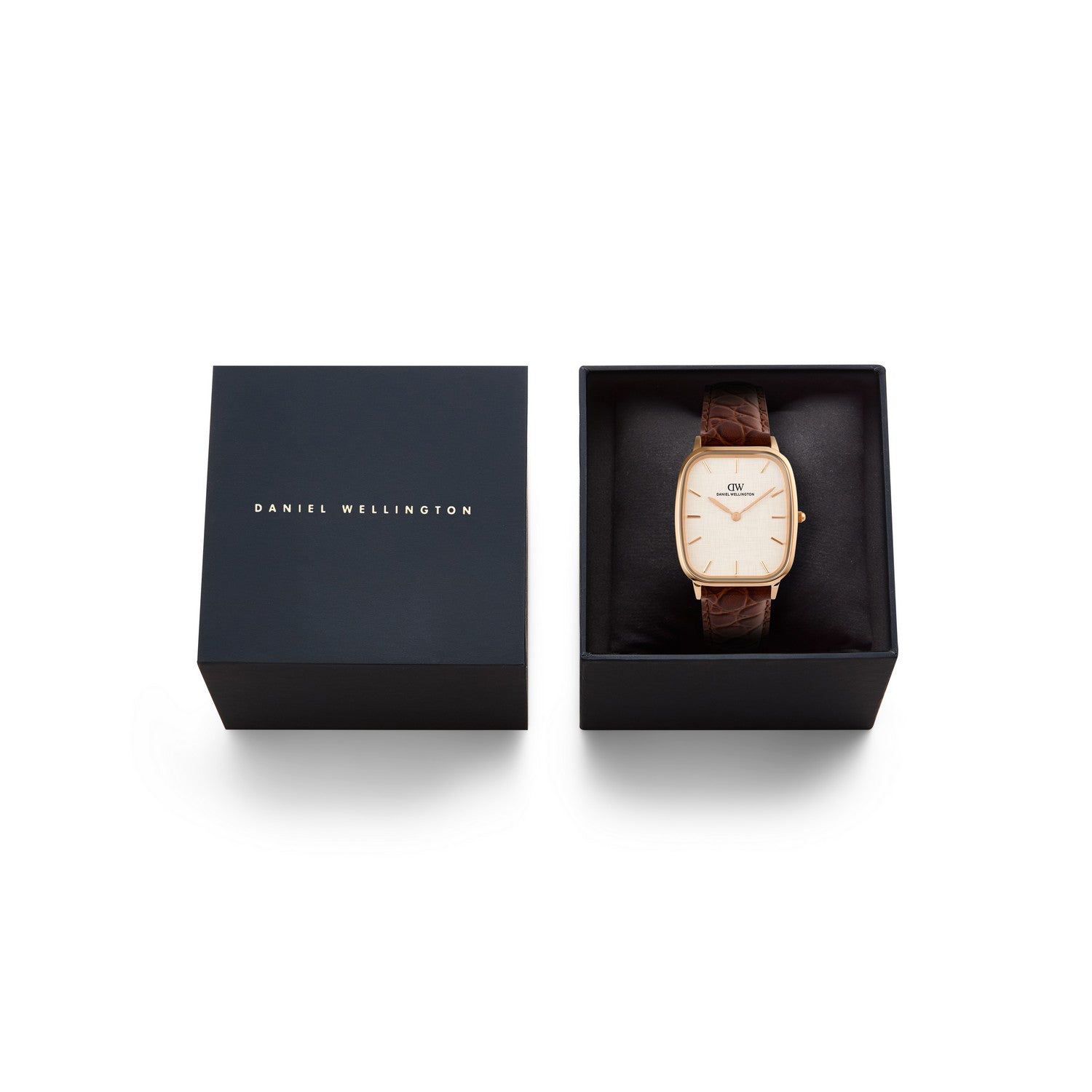 Daniel Wellington watch with a rose gold case, cream dial, and brown leather strap, shown next to its black presentation box on a white background.