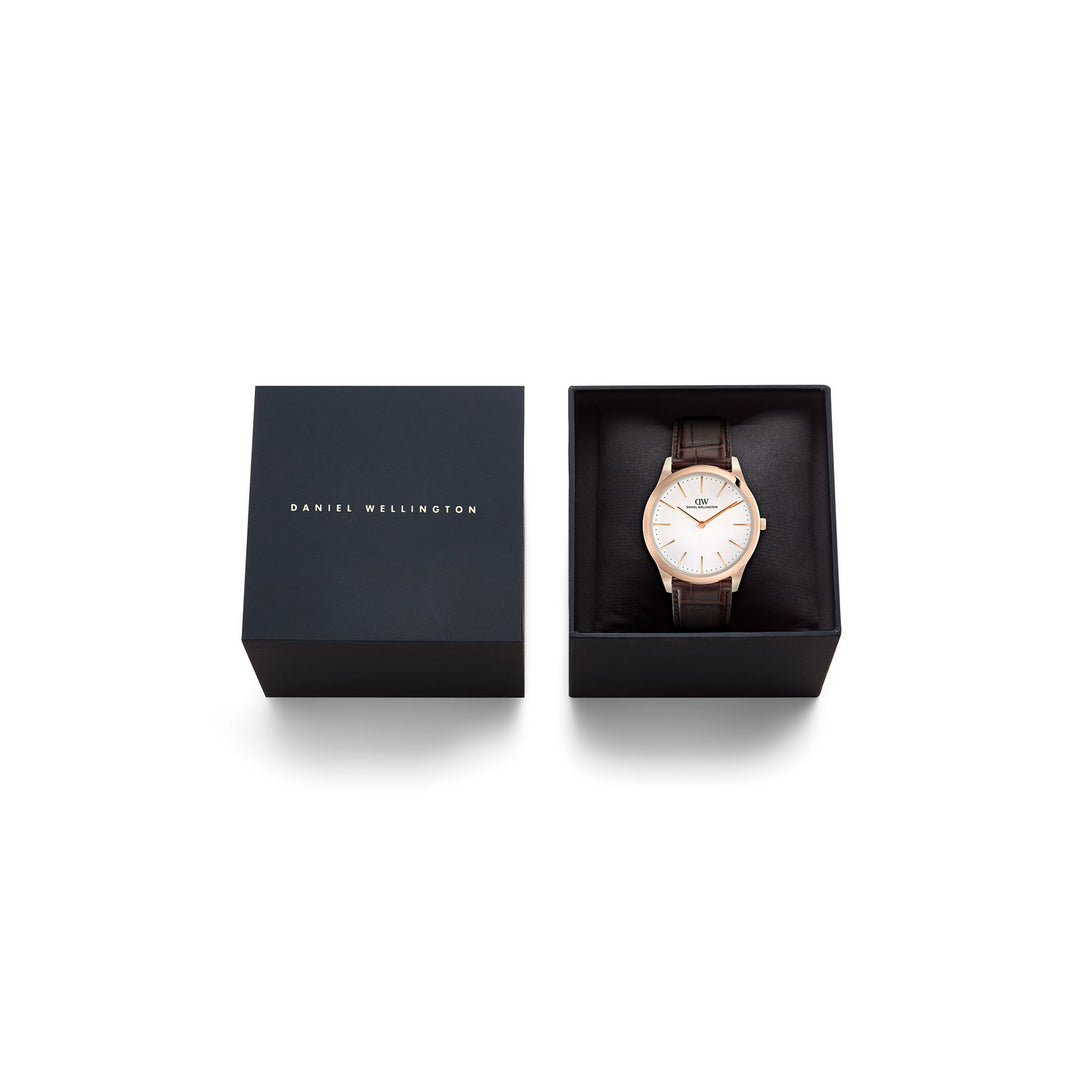 Daniel Wellington wristwatch with a brown leather strap and rose gold case, displayed inside its open black presentation box next to the closed box on a white background.