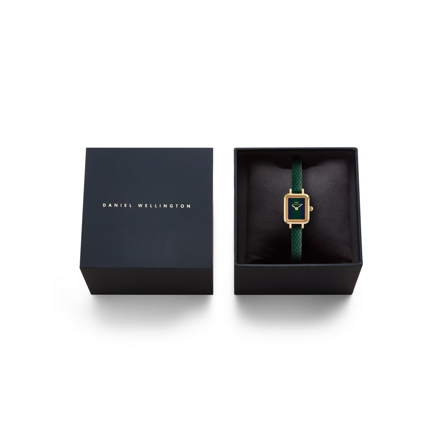 Daniel Wellington gold-tone rectangular watch with a green textured strap, displayed inside an open black presentation box next to its closed lid on a white background.