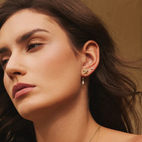 Close-up of a woman wearing star-shaped earrings with a neutral background