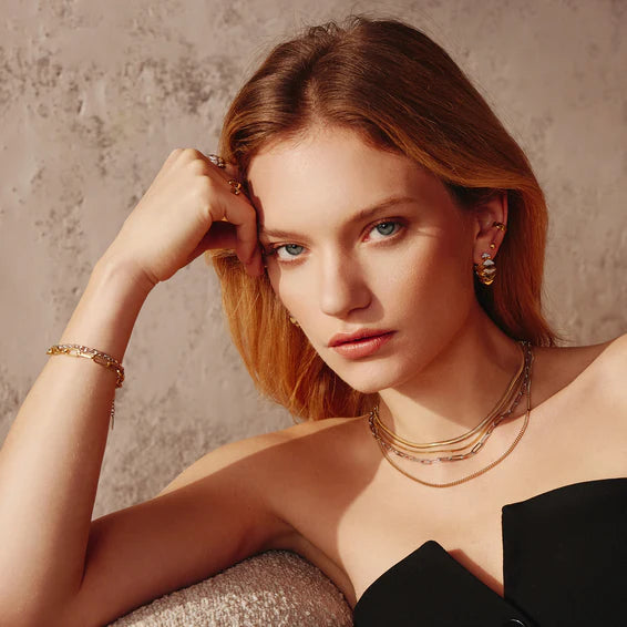 Woman with styled hair and jewelry against a neutral background