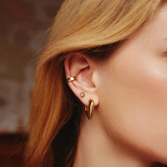 Close-up of a person wearing gold earrings with a blurred background