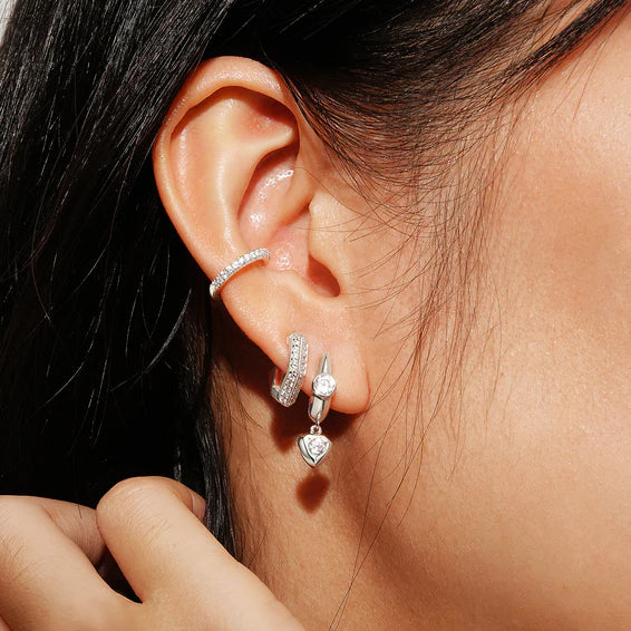 Close-up of an ear wearing multiple diamond earrings with a blurred background