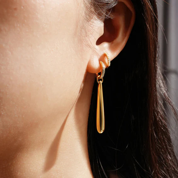 Gold earring worn by a person with dark hair.