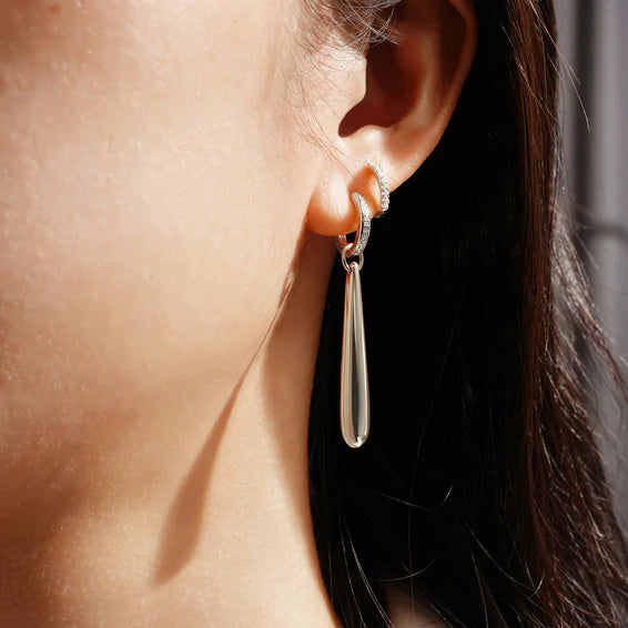 Silver teardrop earring worn by a person with dark hair.