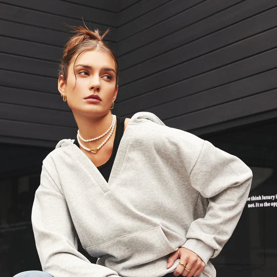 Woman wearing a gray hoodie against a black background