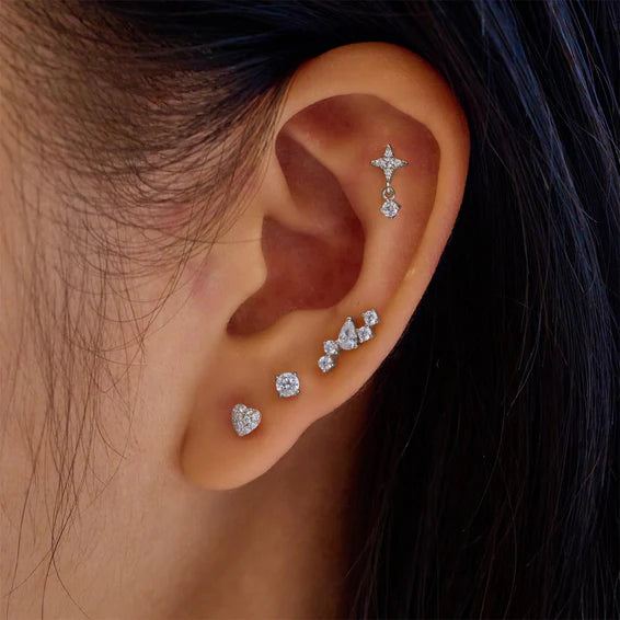 Close-up of an ear wearing multiple diamond earrings with a blurred background.