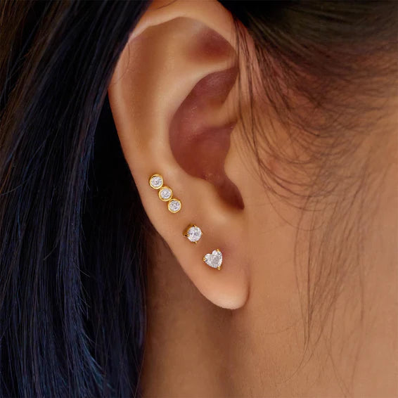 Close-up of an ear wearing multiple diamond earrings with dark hair.