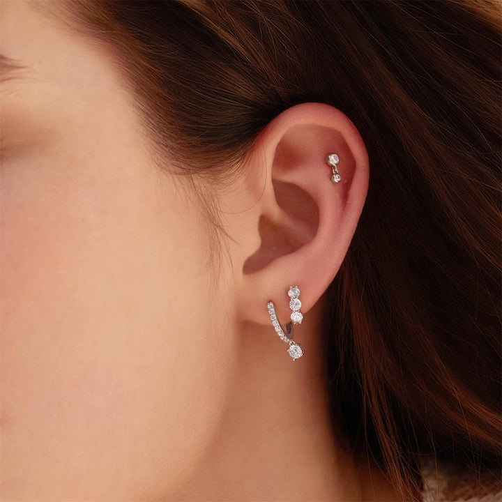 Close-up of a person wearing two pairs of earrings.
