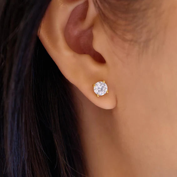 Close-up of a diamond earring on an ear with dark hair.
