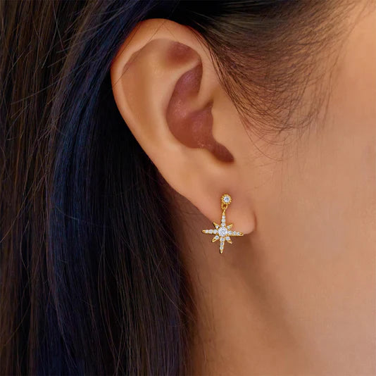Gold star-shaped earring worn by a person with dark hair.