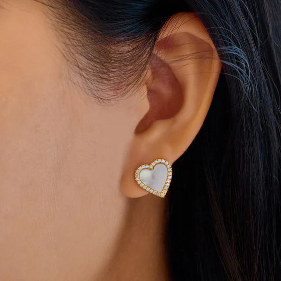 Heart-shaped earring worn by a person with dark hair.