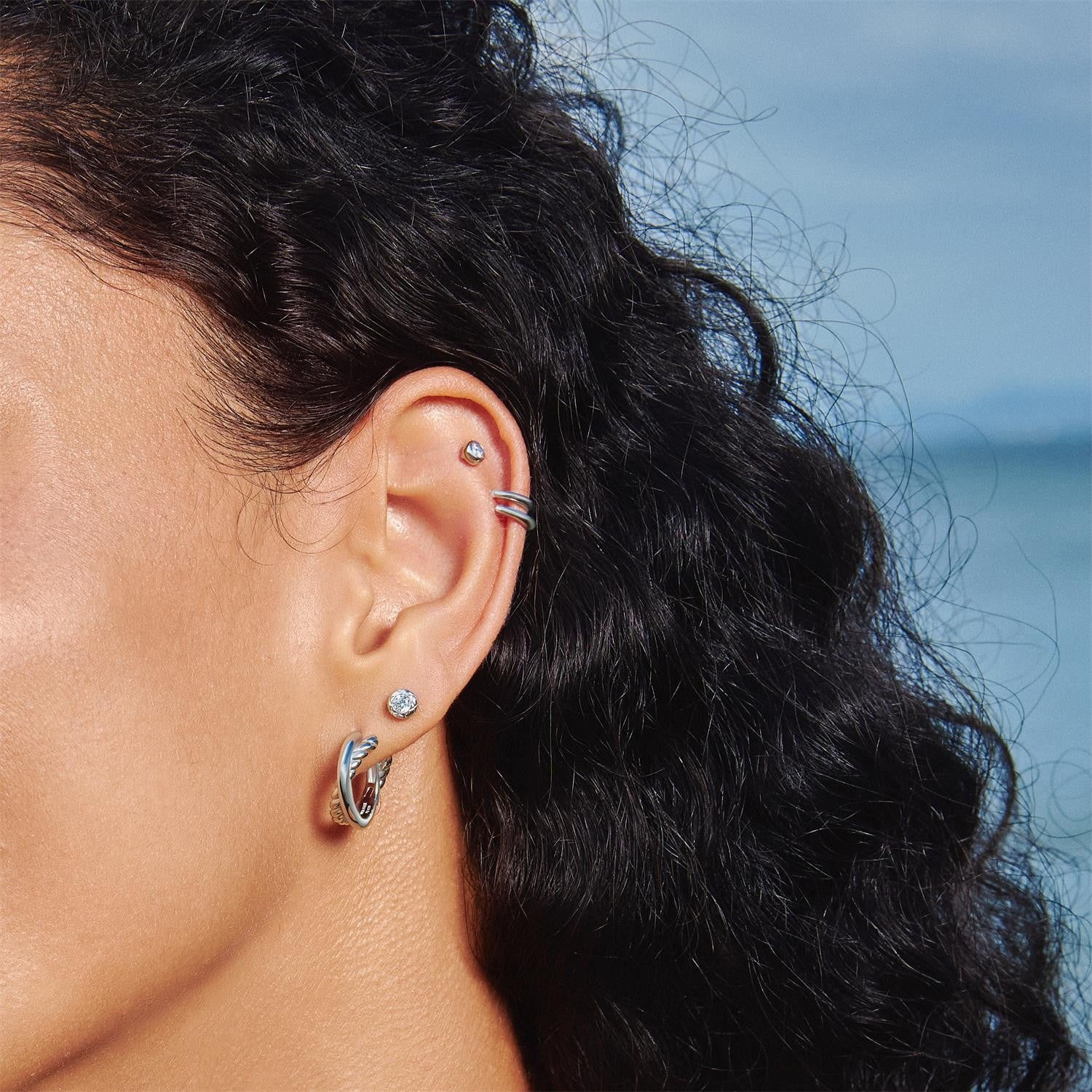 Close-up of a person's ear with earrings against a blurred natural background